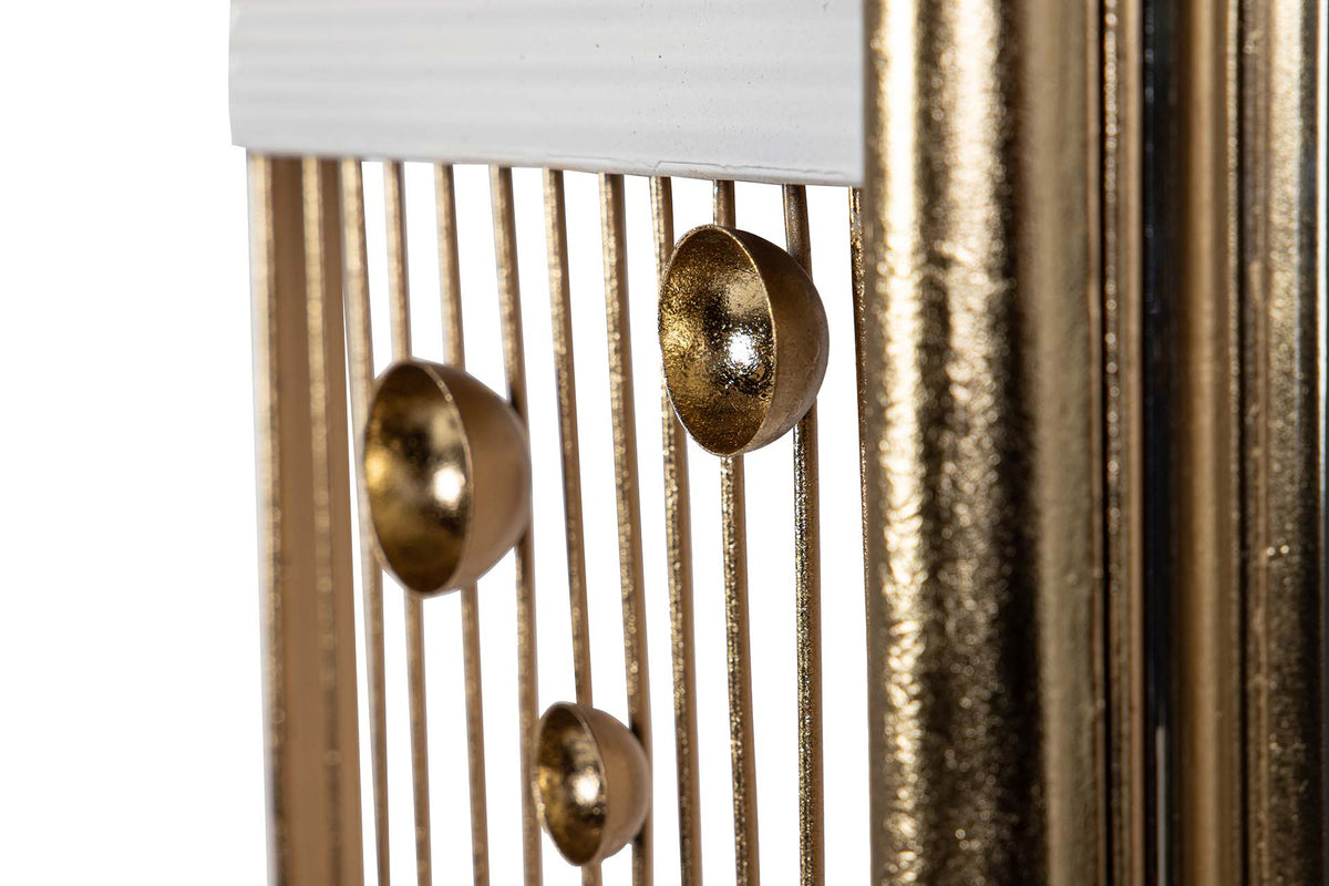 Close-up of a decorative gold-toned metal wall hanging or sculpture with vertical bars, a white rectangular top panel, and three dome-shaped metallic accents | KULORI Malta & Gozo