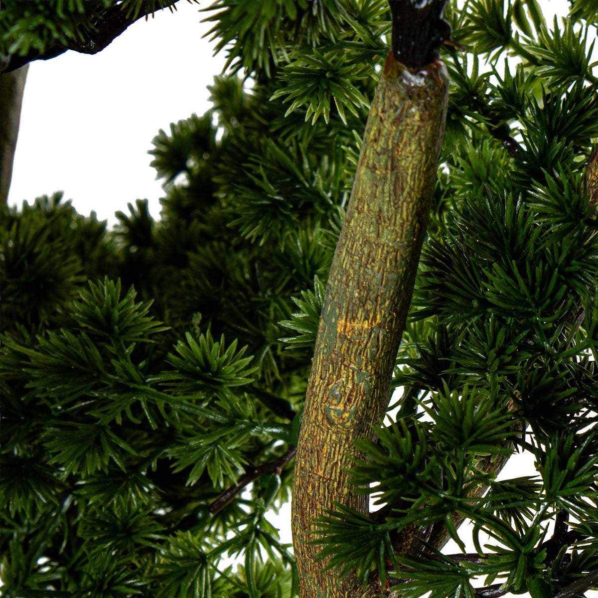 Close-up of artificial green tree branches with textured brown trunks and dense needle-like foliage | KULORI Malta & Gozo