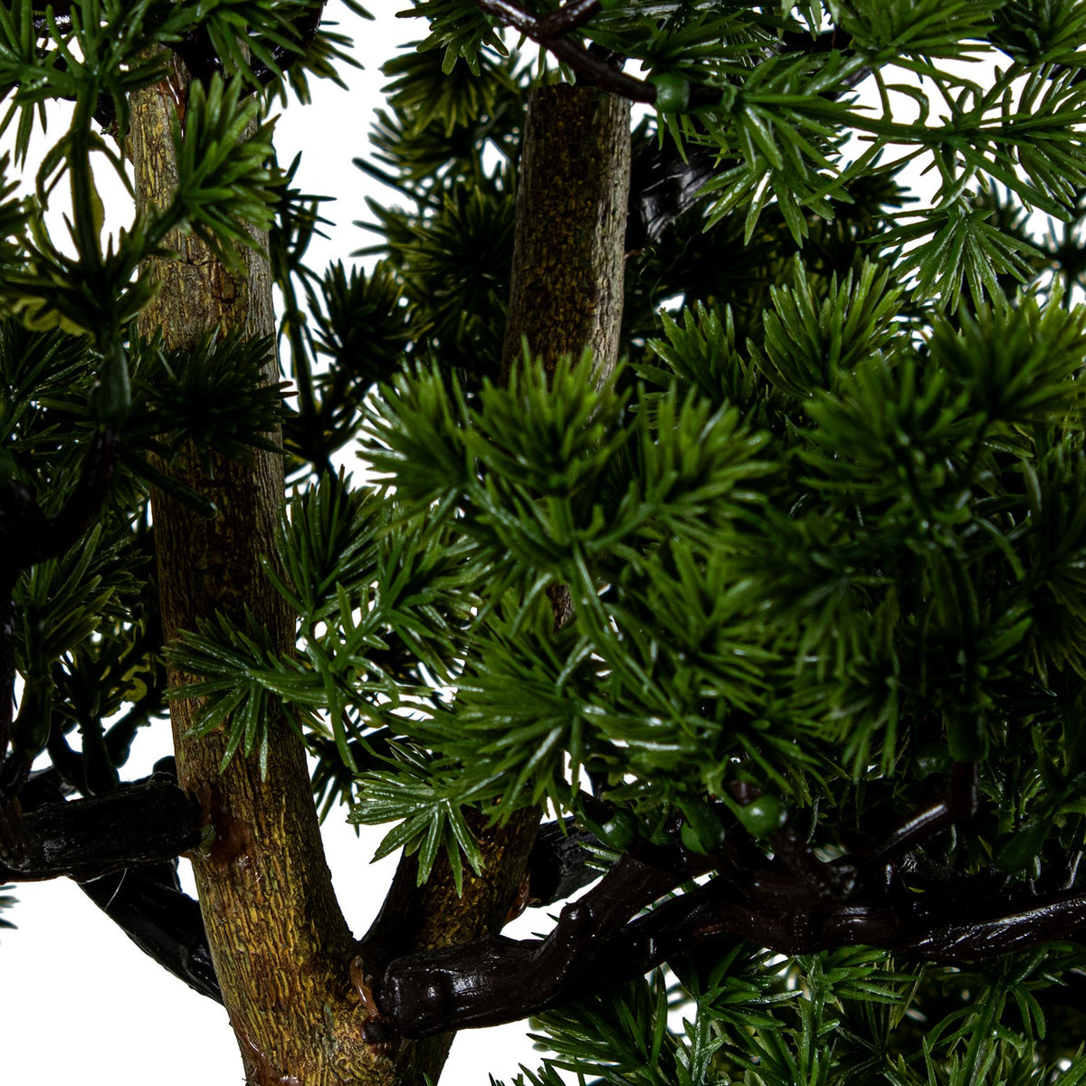 Close-up of artificial pine tree branches with dense green needles and brown trunk | KULORI Malta & Gozo