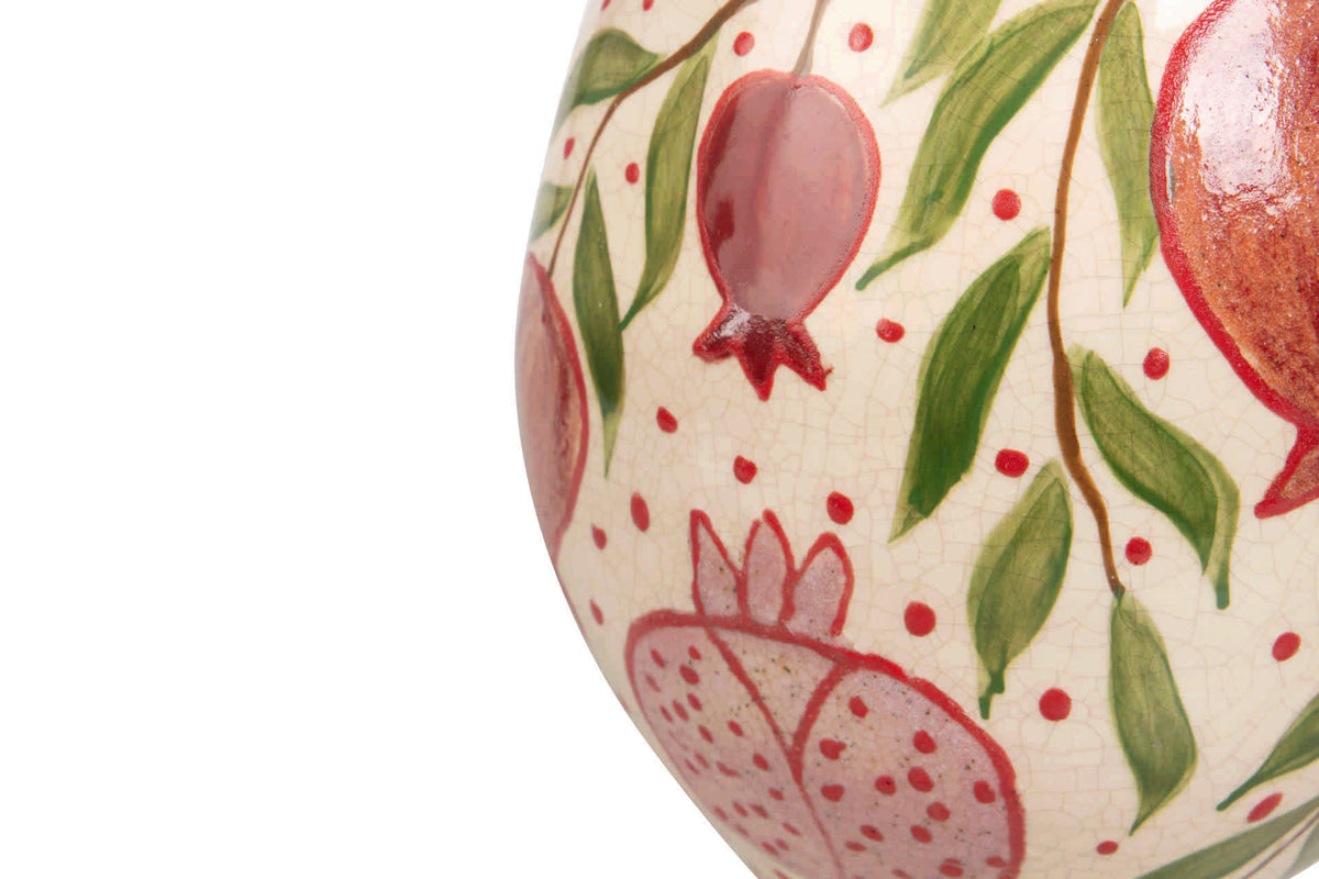 Close-up of a ceramic vase decorated with hand-painted pomegranate motifs in red and pink on a cream background with green leaves | KULORI Malta & Gozo
