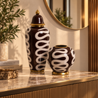 Two decorative ceramic vases with a glossy dark brown and white wavy pattern and gold trim, displayed on a marble console table in a styled interior setting | KULORI Malta & Gozo