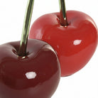 Two glossy cherry-shaped decorative objects with dark green stems, one deep red and one dark burgund | KULORI