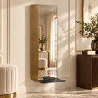 A tall, narrow wall mirror with a brushed gold frame and a black shelf-like base, mounted on a cream paneled wall in a styled interior room  | KULORI Malta & Gozo