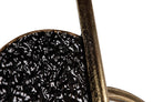 Close-up detail of a black textured circular object with a distressed bronze metal rod and ring | KULORI Malta & Gozo