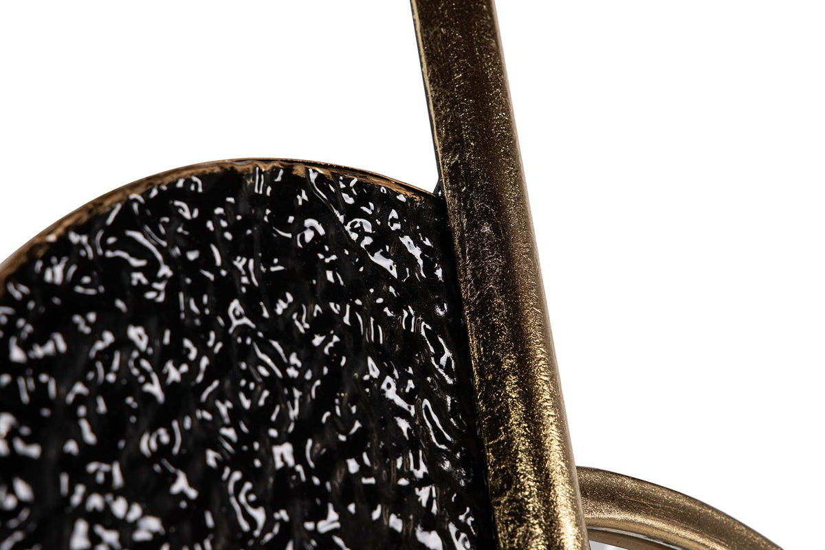 Close-up detail of a black textured circular object with a distressed bronze metal rod and ring | KULORI Malta & Gozo