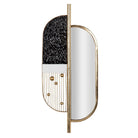 An oval wall mirror with a split design, featuring a textured black and white vertical panel on one side and a polished gold frame on the other | KULORI Malta & Gozo