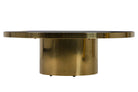 A modern round coffee table featuring a brushed brass cylindrical pedestal base and a matching round brass top with a dark inlay | KULORI Malta & Gozo