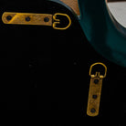 Close-up of a teal and black electric guitar body showing two brass hardware pieces, likely tailpiece and bridge plate components  | KULORI Malta & Gozo