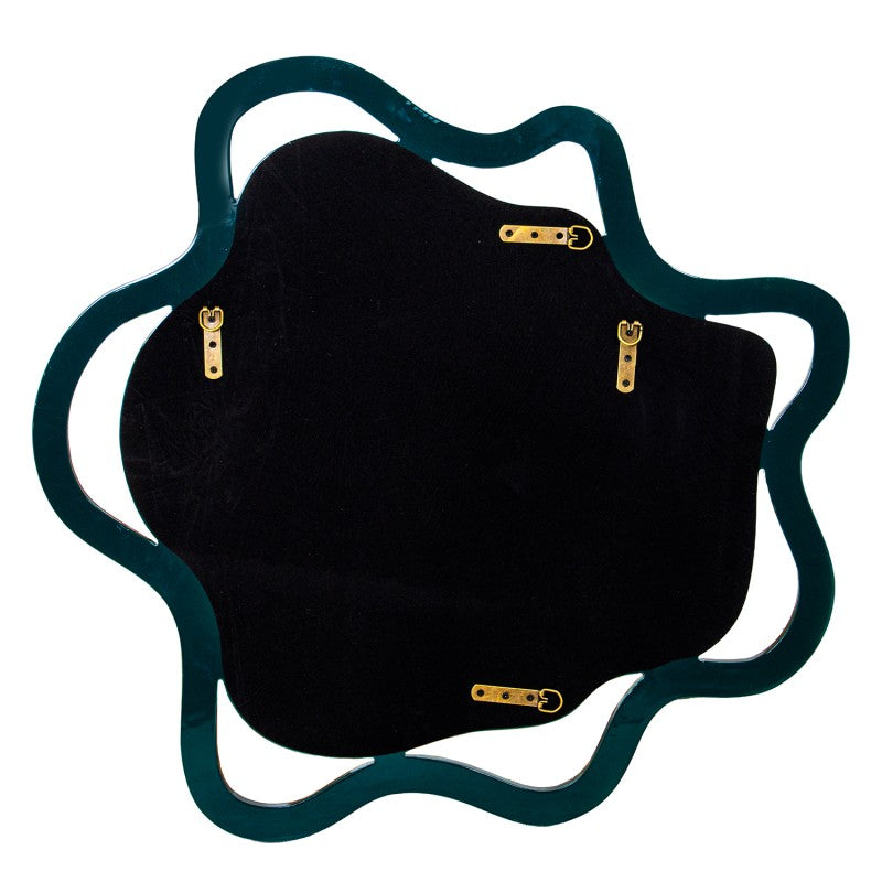 An irregularly shaped wall mirror with a dark teal wavy frame and a black velvet backing, featuring four gold metal mounting brackets | KULORI Malta & Gozo