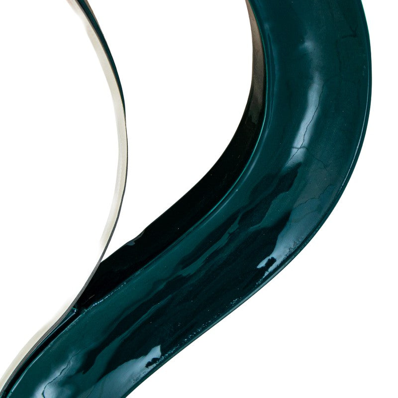 A close-up of a glossy, dark teal-green curved object, likely a mirror edge or glass panel | KULORI Malta & Gozo