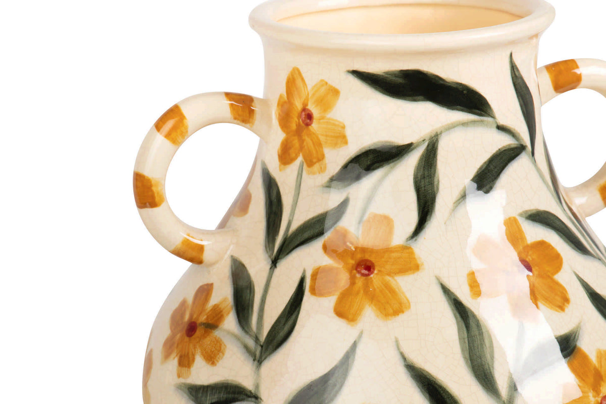 Close-up of a ceramic vase with two loop handles, decorated with orange-yellow flowers and green leaves.
