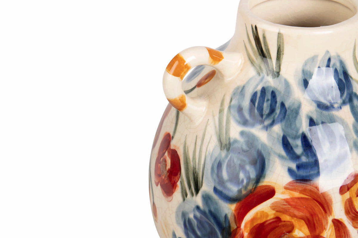 Close-up of a ceramic vase with a rounded body, small loop handle, and hand-painted floral pattern in blue, orange, and red