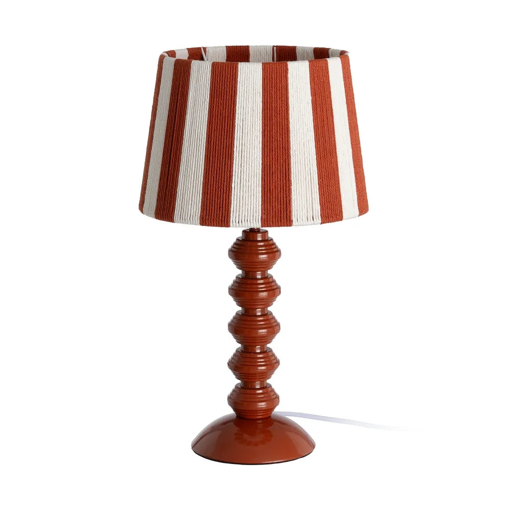 A table lamp with paper rope shade featuring vertical terracotta and off-white stripes, supported by a glossy reddish-brown turned wood bead spindle base on a white background.